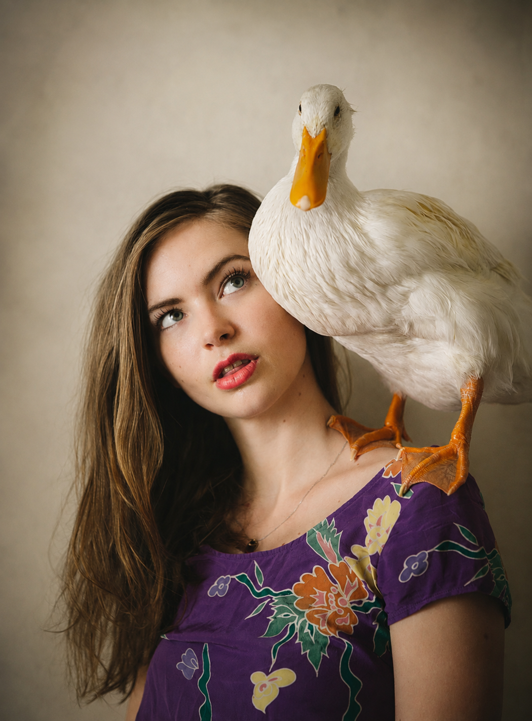 Model in a purple floral dress with a white duck perched on her shoulder