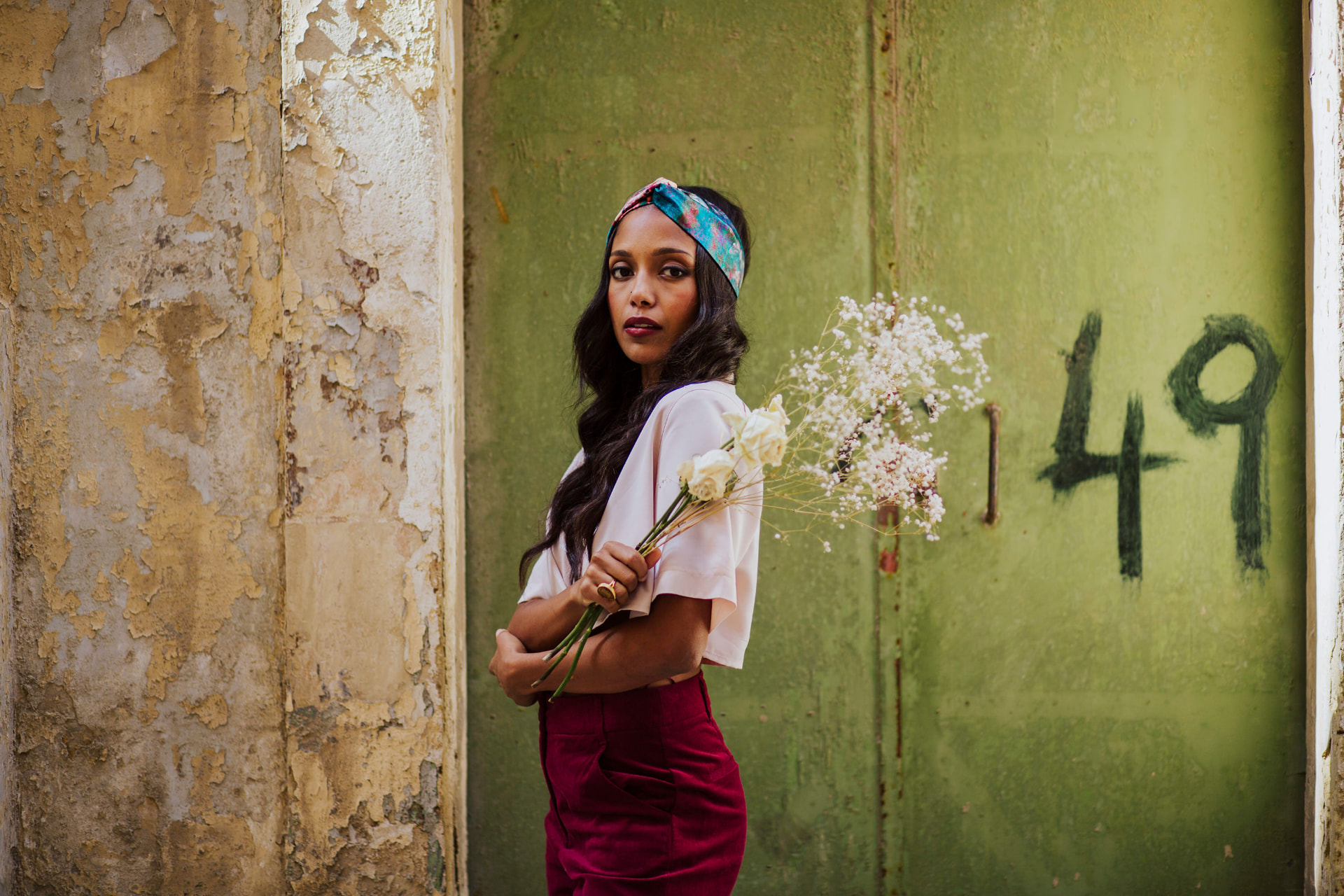 Model holding white roses against a green door