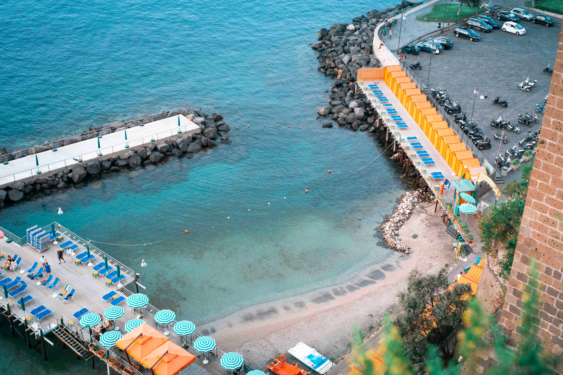 Aerial view of a Sorrento swimming bay with striped umbrellas and orange beach huts