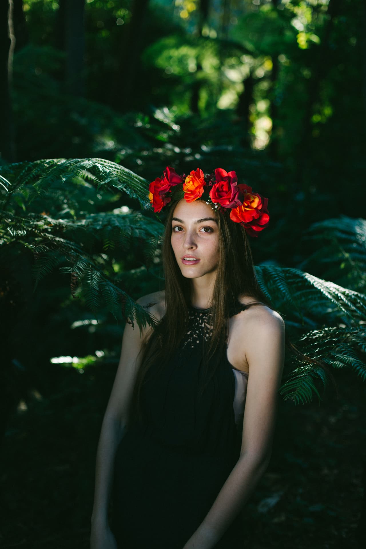 Portrait of a woman in a red flower crown among ferns
