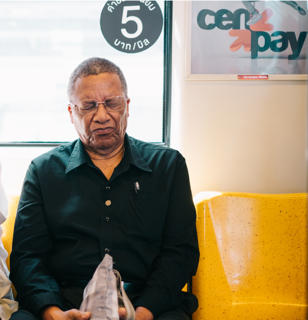 Man resting on a yellow train seat on the Bangkok Skytrain