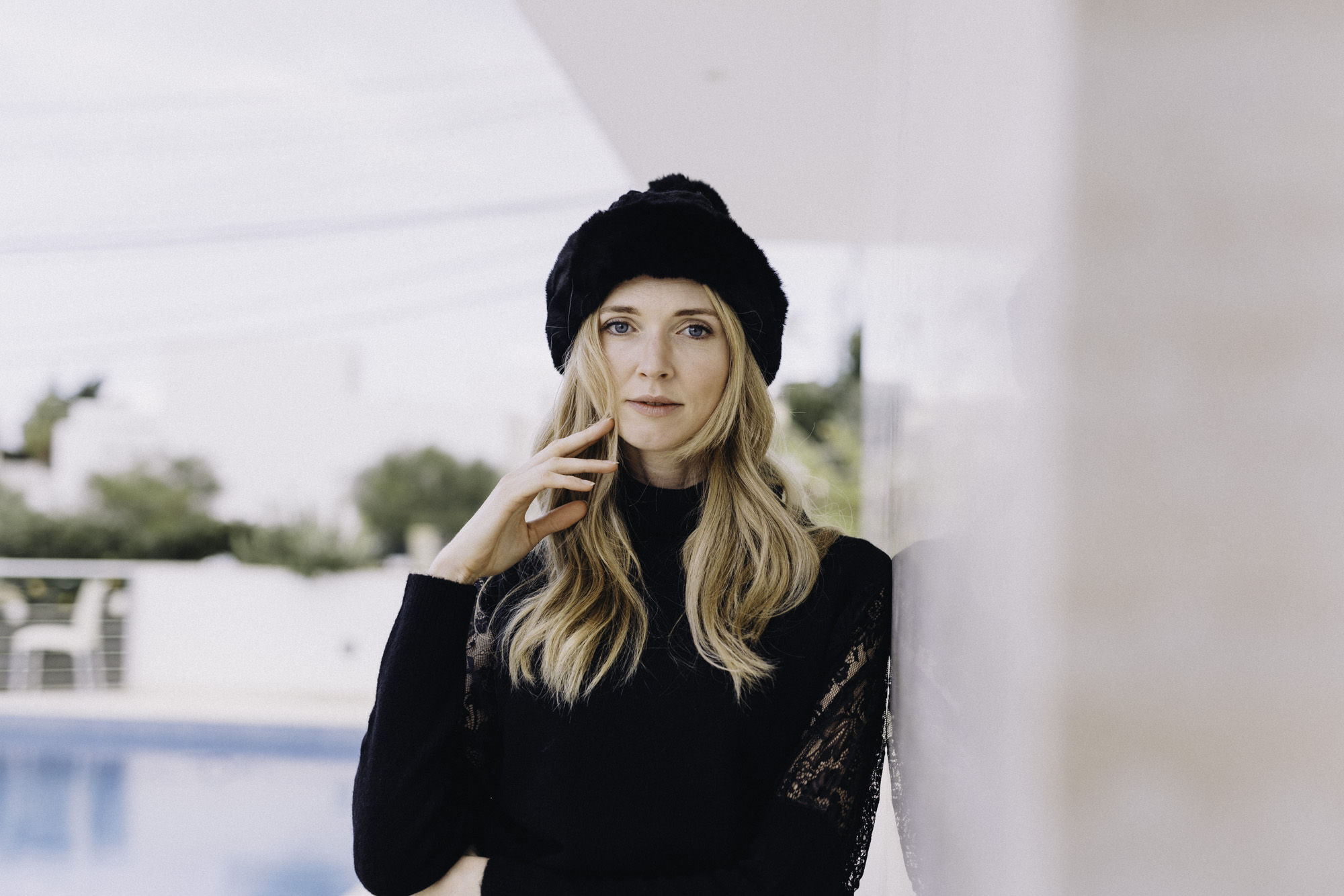 Portrait of a model in black with a fur hat beside a pool