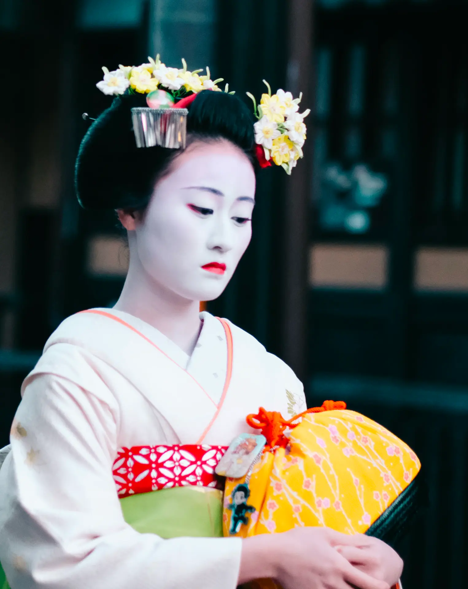 Maiko in a white kimono with blossom hair ornaments in Kyoto