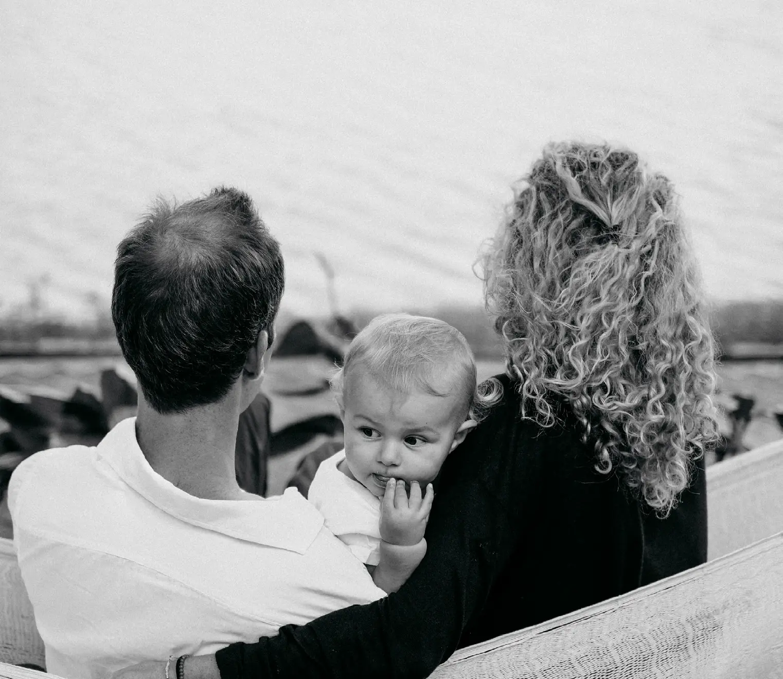 Black and white photograph of parents and their baby looking out to the water