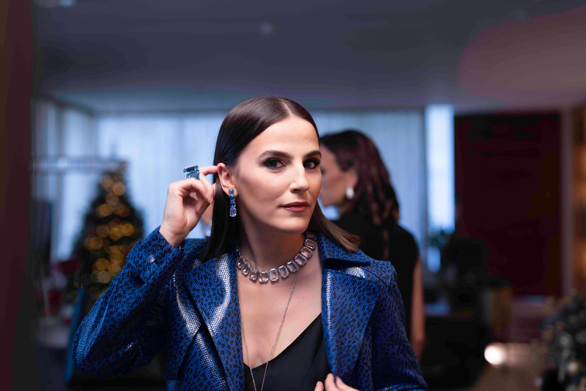Woman in a blue snakeskin jacket wearing an aquamarine necklace and earrings