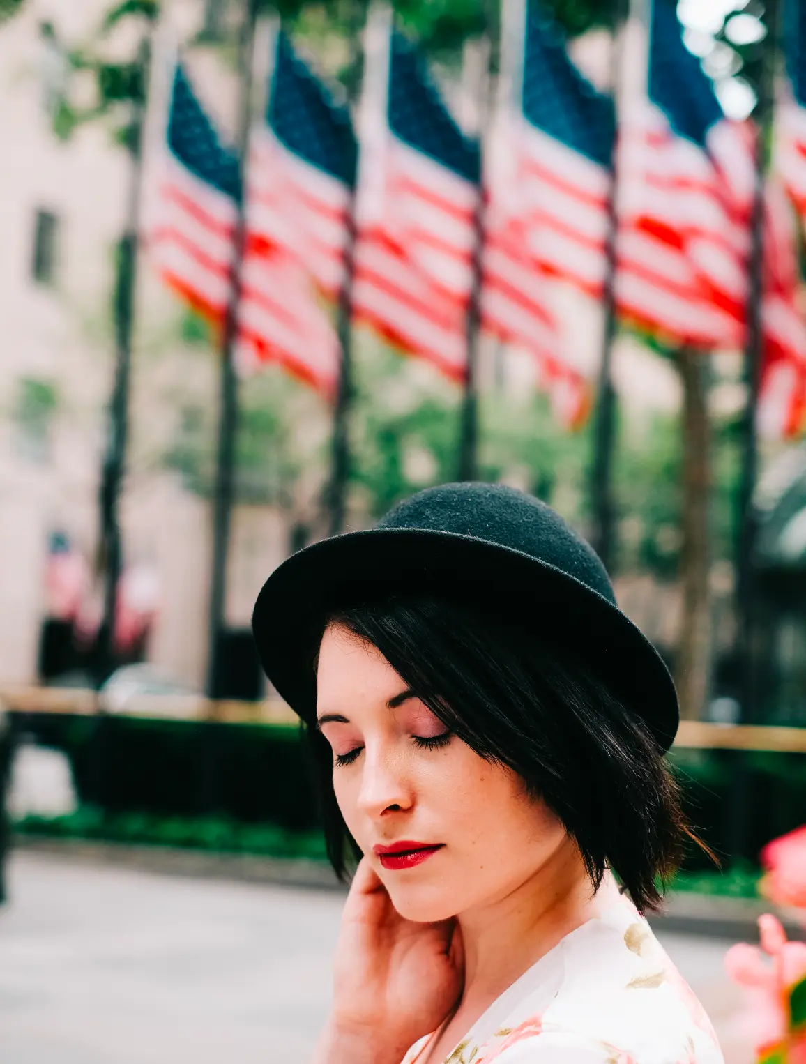 Portrait of a woman in a black hat before rows of American flags