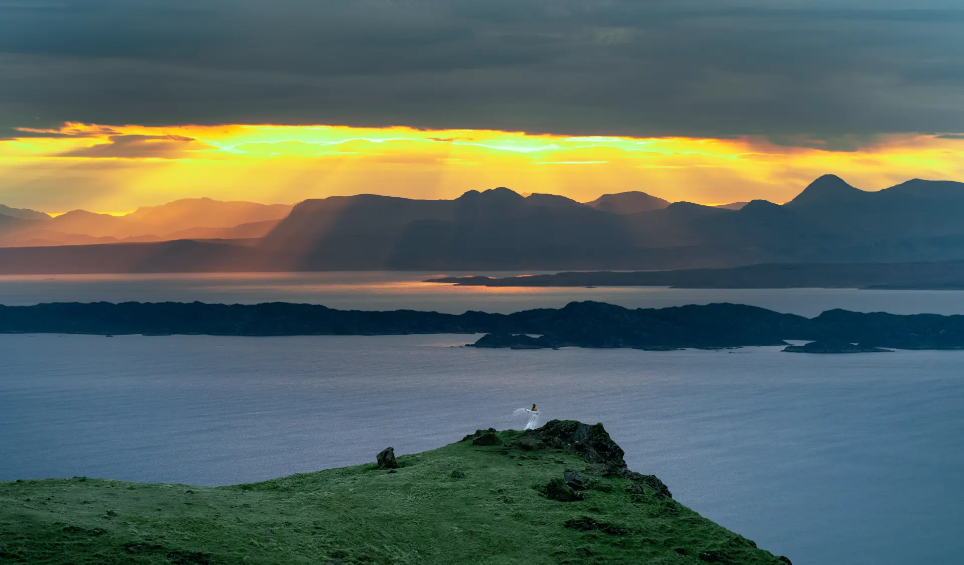 Figure in white on a headland at golden sunset over the sea