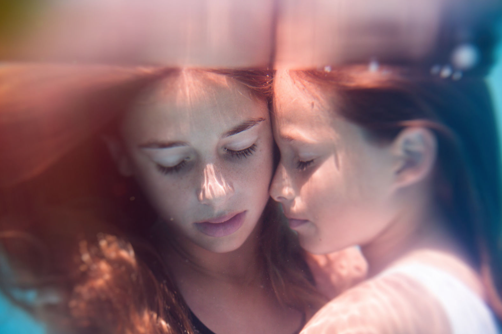 Two faces meeting at the waterline, mirrored in the surface