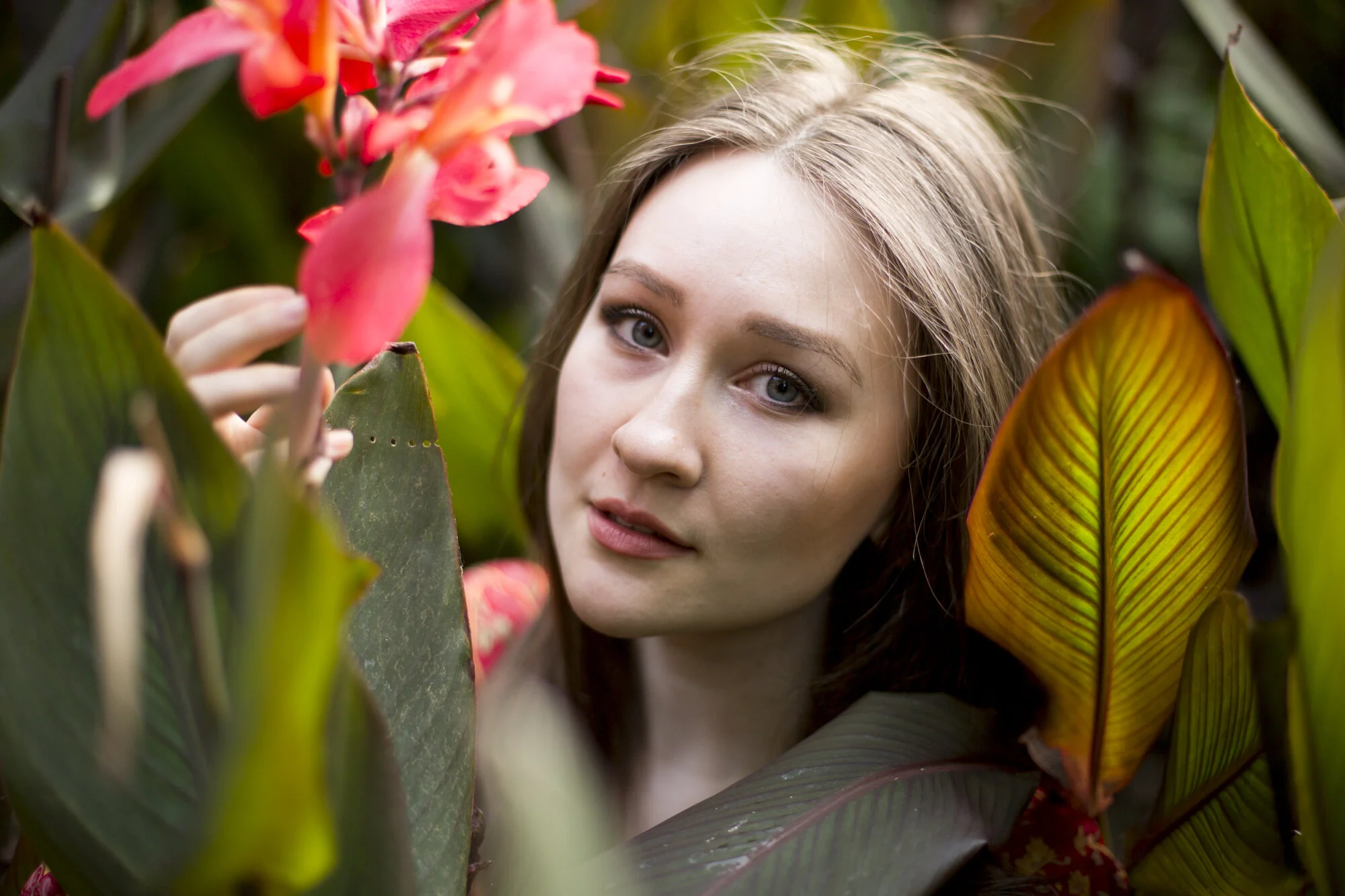 Portrait of a woman among tropical canna lilies and green leaves