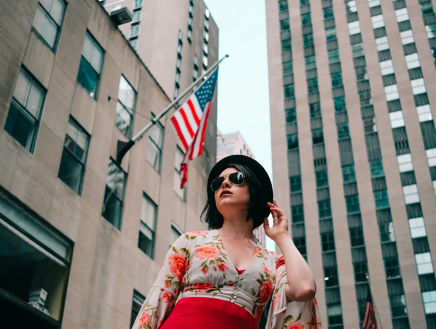 Woman in a floral wrap and red skirt beneath Manhattan skyscrapers and a flag