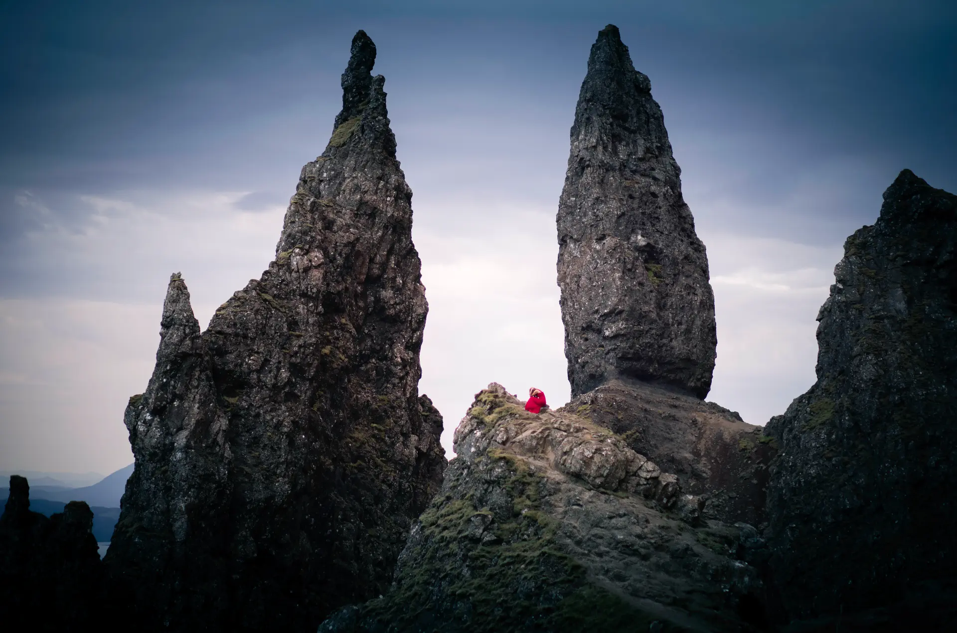 Figure in red seated between the pinnacles of the Old Man of Storr