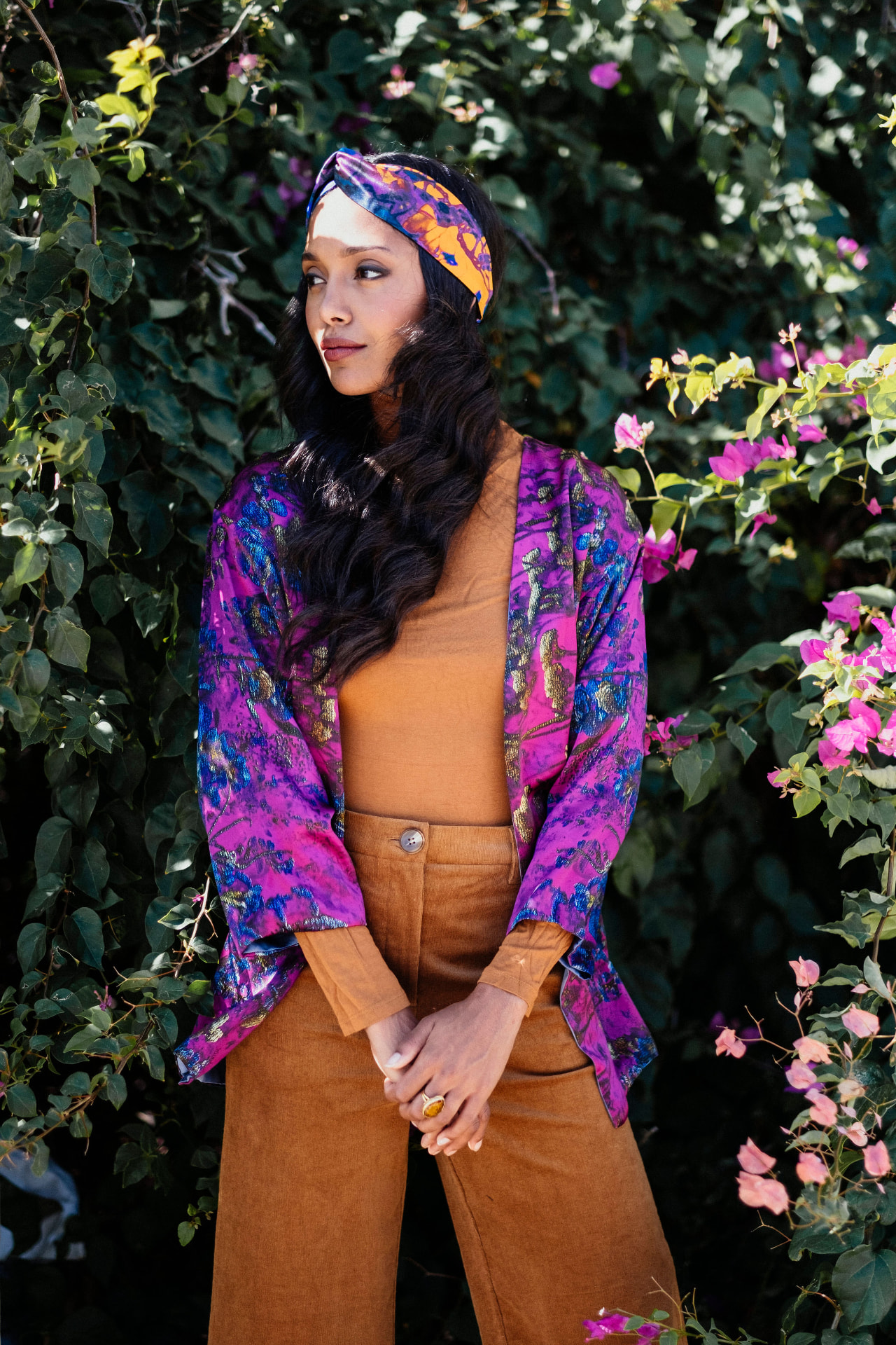 Model in a magenta metallic jacket among bougainvillea