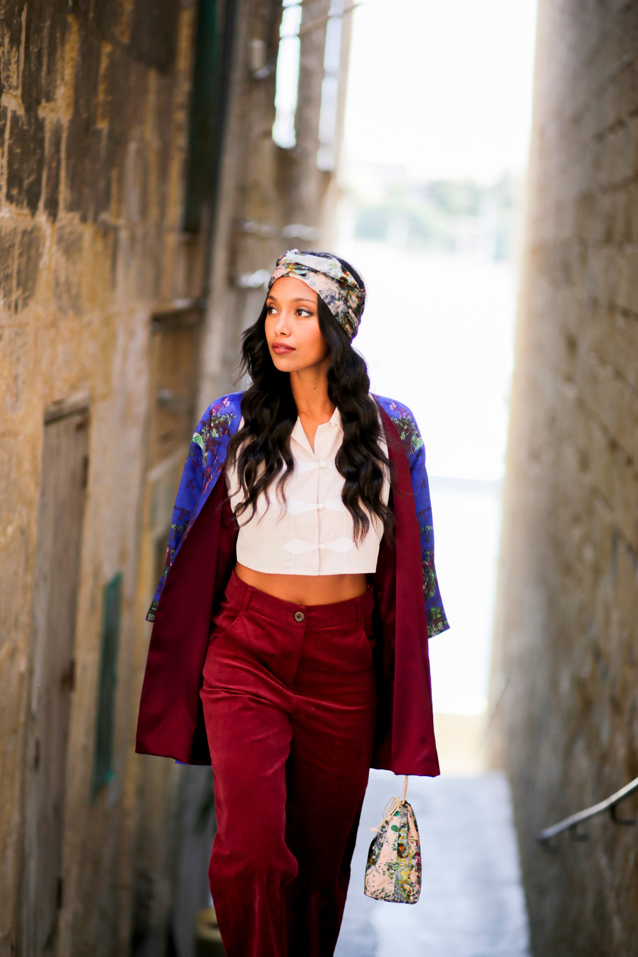 Model in burgundy velvet walking a narrow Malta alley