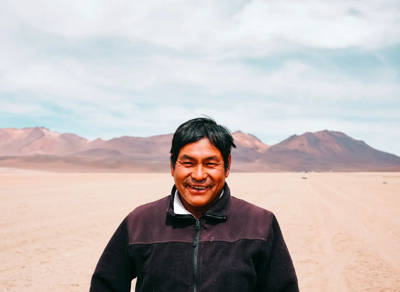 Smiling Bolivian guide before the mountains of the altiplano