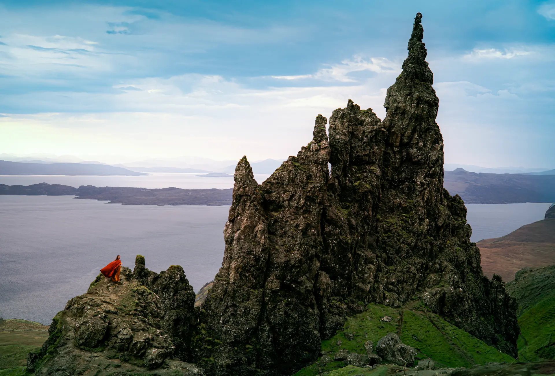 Woman in red beside the Old Man of Storr rock pinnacles