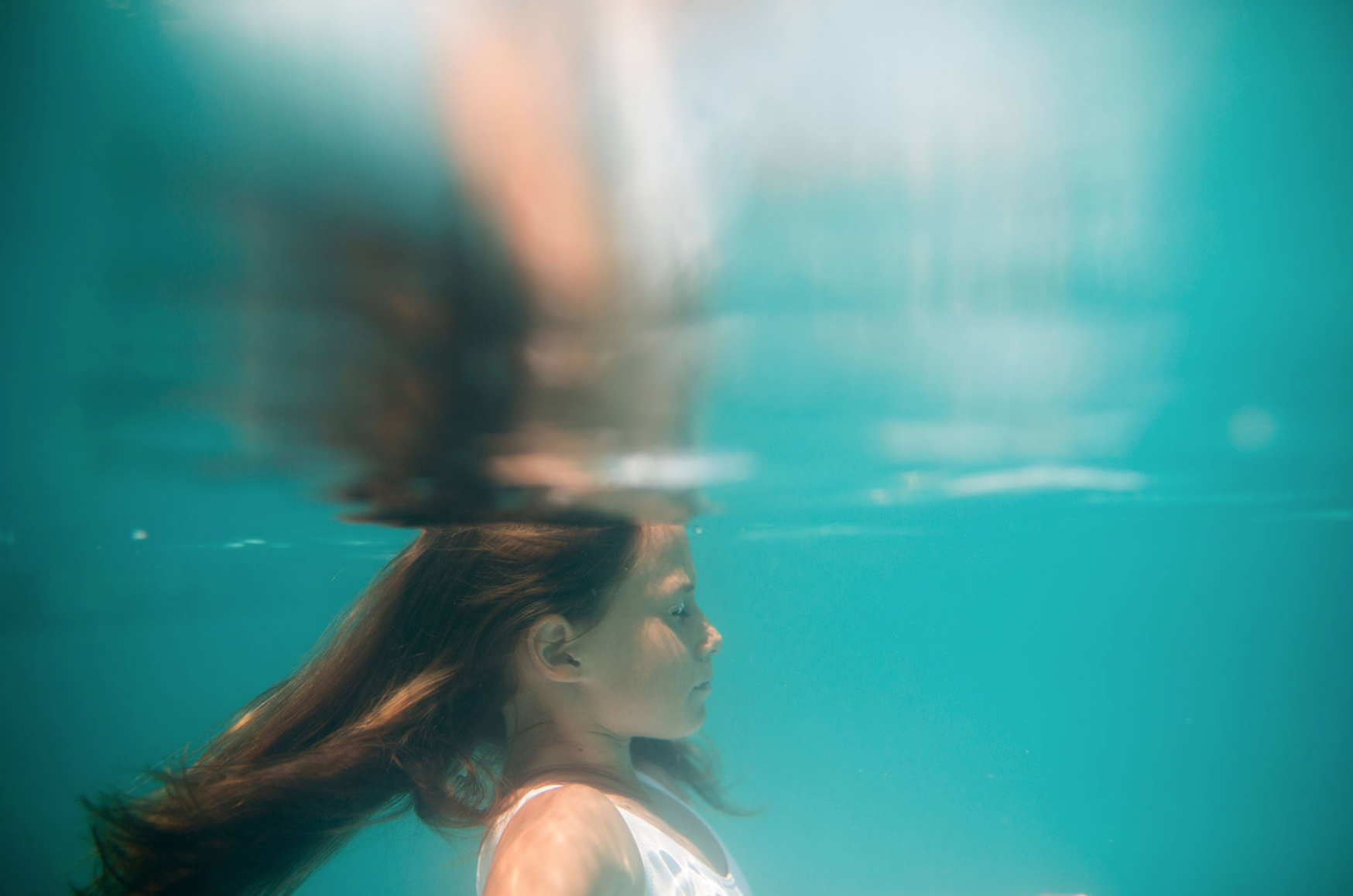 Girl in profile beneath the surface, hair fanning out in blue water