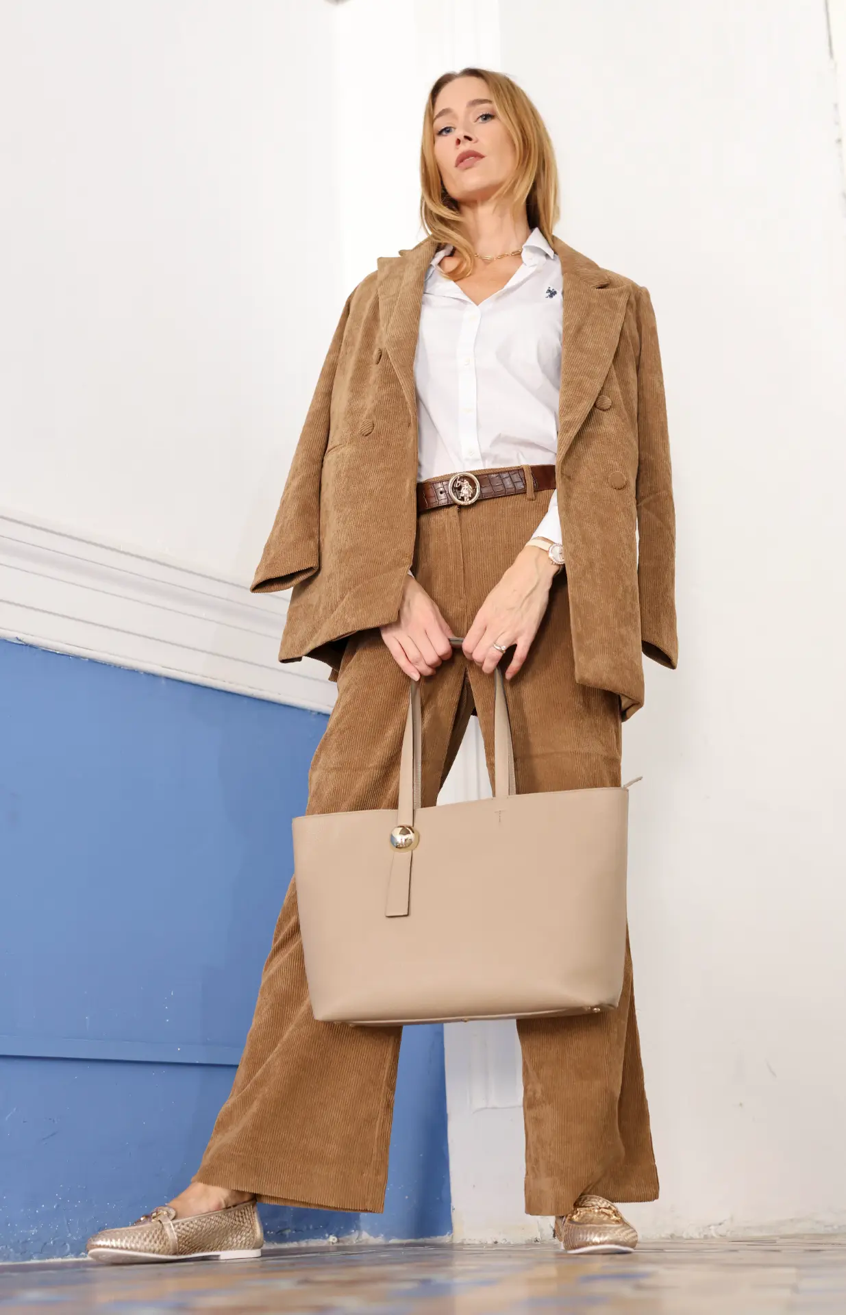 Model in a tan corduroy suit with a taupe leather tote
