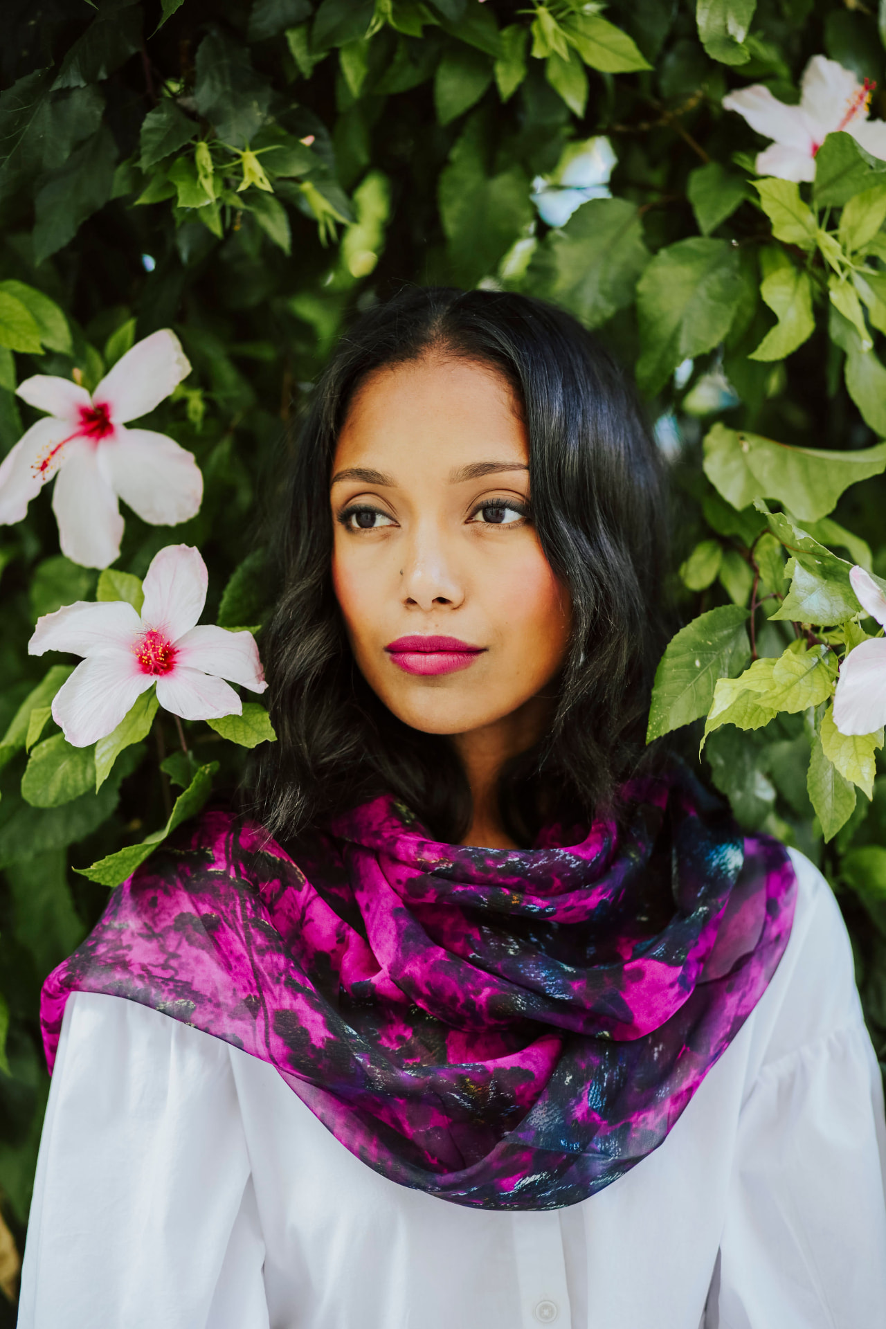 Model in a pink printed silk scarf among hibiscus flowers