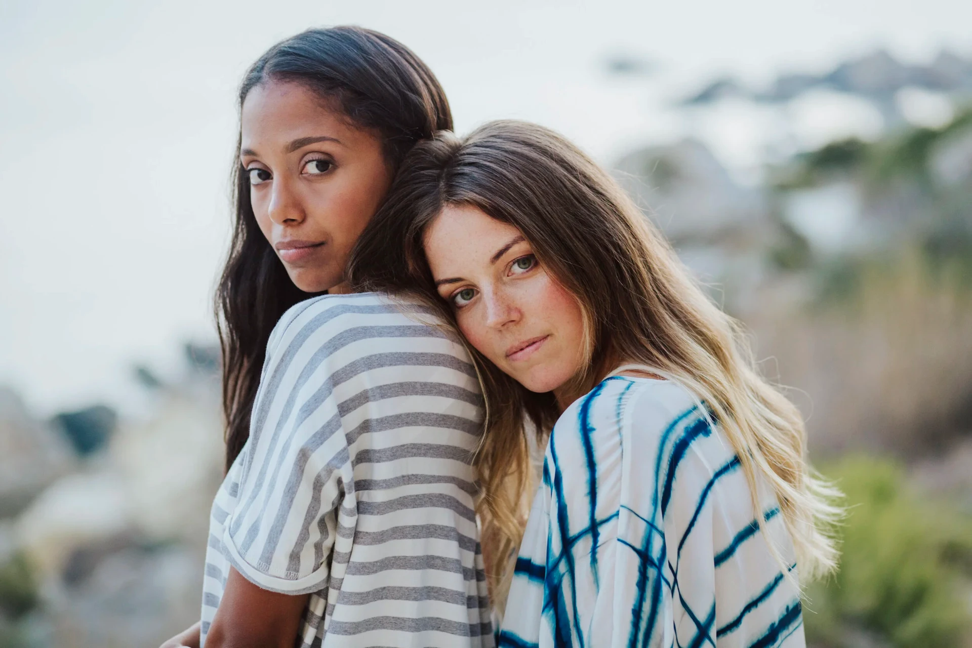 Two models back to back in striped and tie-dye kaftans on the coast
