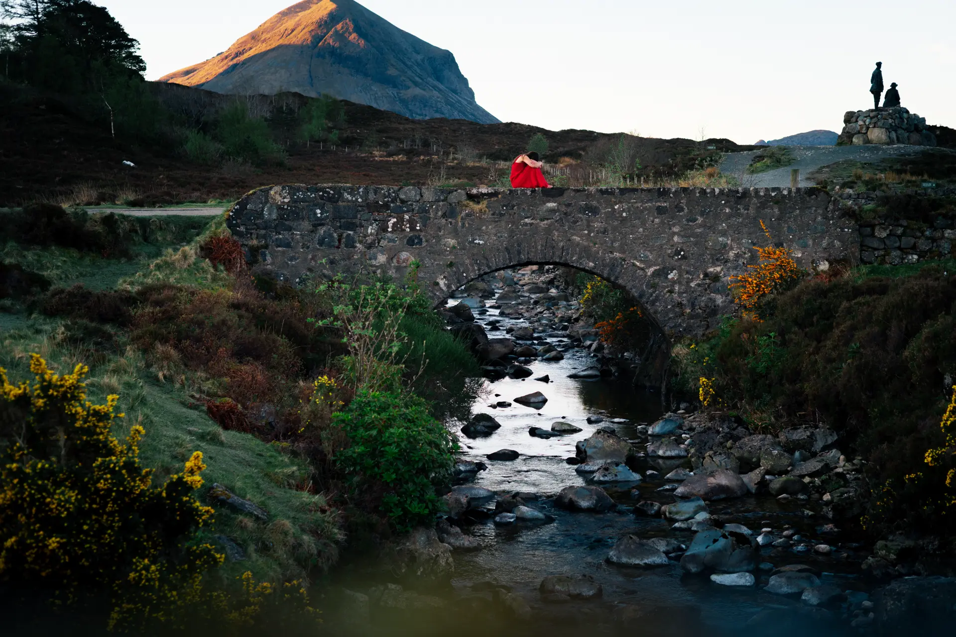 Figure in red resting on the Sligachan bridge at dawn